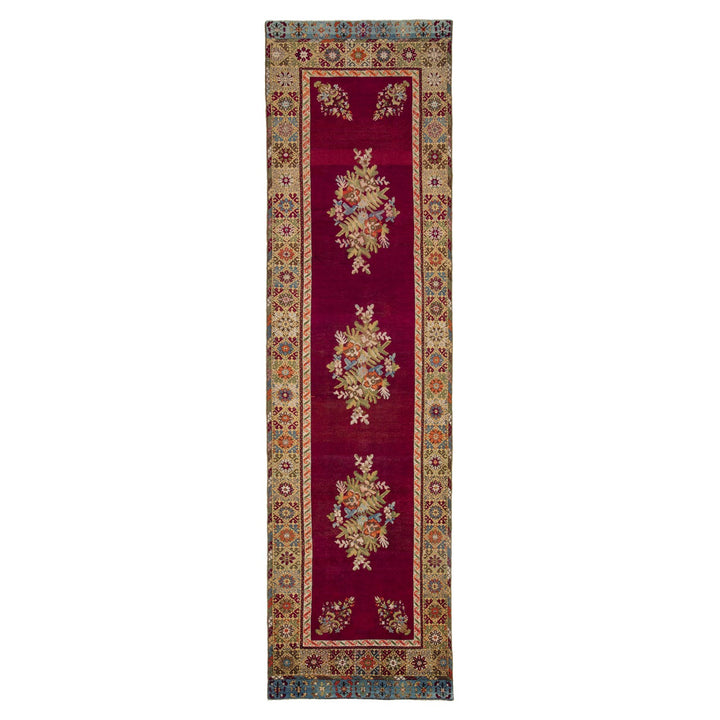 Rich maroon runner rug with symmetrical floral motifs and ornate border.
