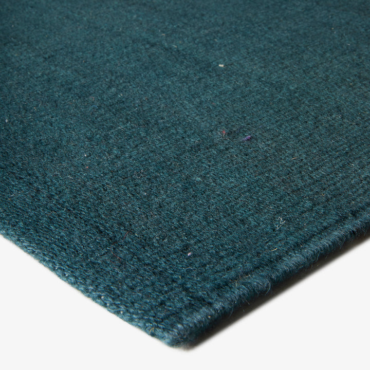 Close-up of teal or dark green textured fabric with dense fibers.