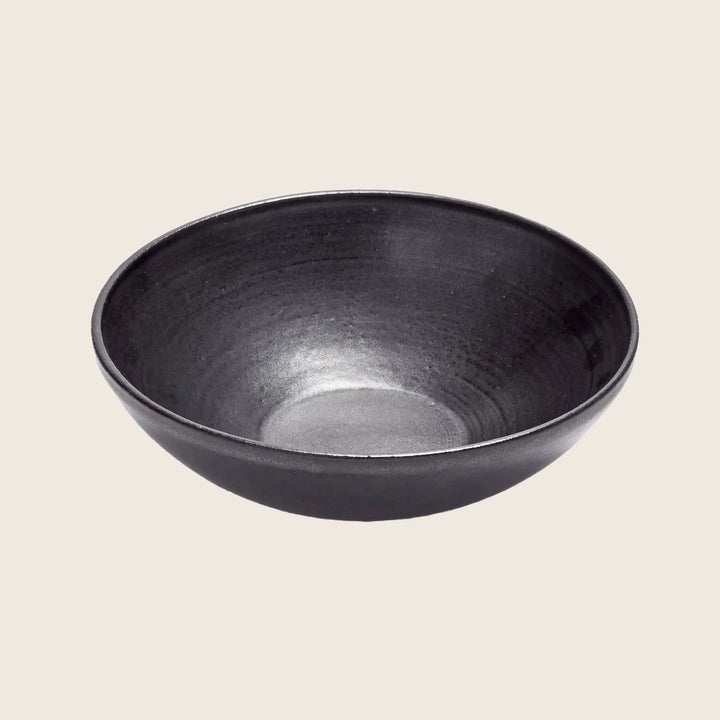 Simple black ceramic bowl on white background with textured pattern.