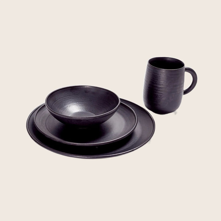 Modern black dishware set on white background, minimalist design aesthetic.