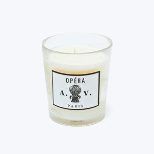 Elegant white candle in glass vessel with Parisian label design.