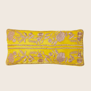 Vibrant yellow pillow with intricate floral embroidery in contrasting tones.