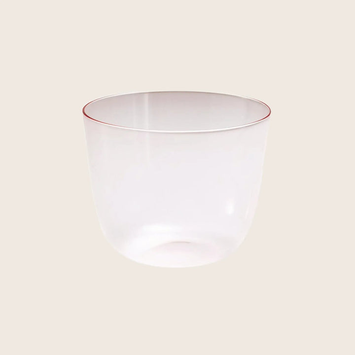 Translucent glass tumbler with a subtle red rim on white background.