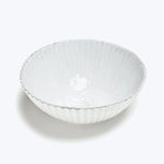 Textured white ceramic bowl with rippled design on white background.