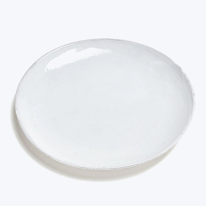 Handcrafted white ceramic dinner plate with rustic texture, empty background.