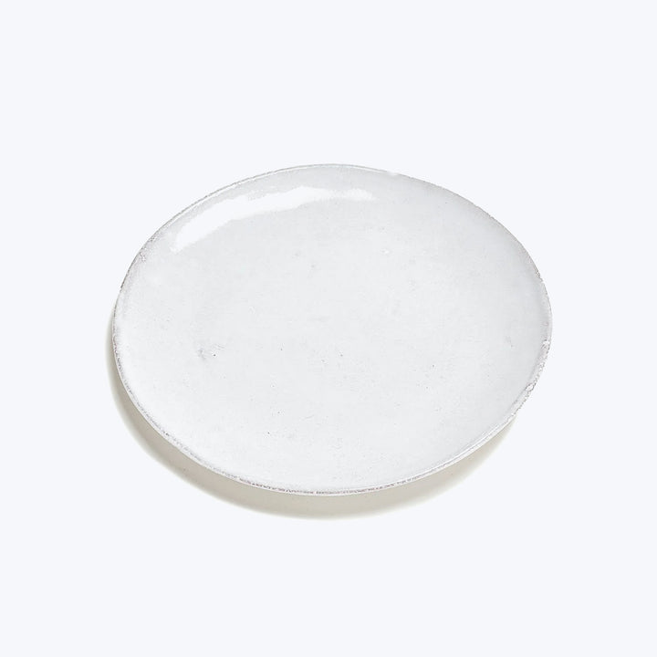 Handmade round ceramic plate with rustic design on white background.
