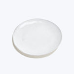 Handmade round ceramic plate with rustic design on white background.