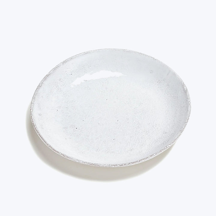 Artisanal ceramic plate with textured finish on white background closeup.