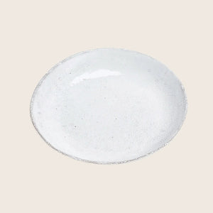 Artisanal ceramic plate with textured finish on white background closeup.