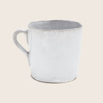 Rustic white ceramic mug with worn rim embodies minimalist charm.