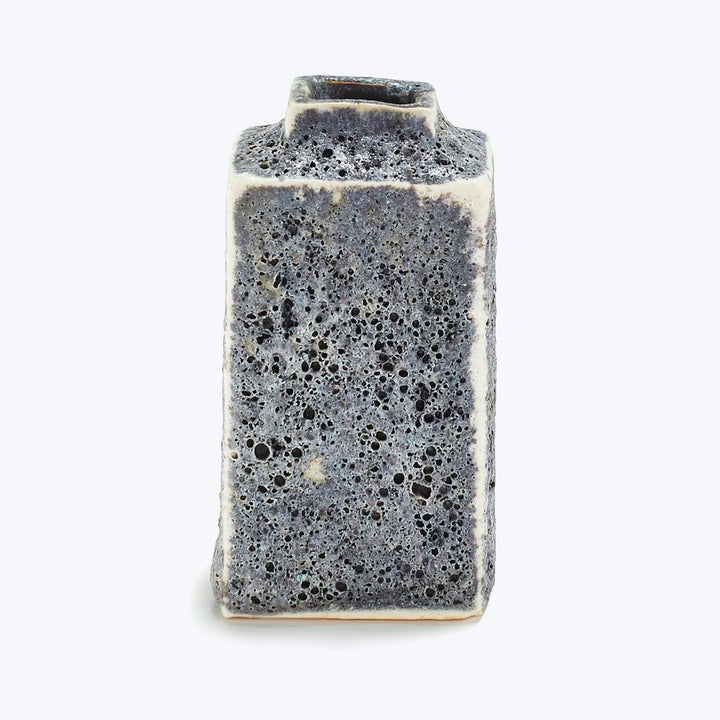 A textured gray block with pores, standing upright on white.
