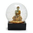Snow globe with golden Buddha figure creates serene and mystical ambiance.