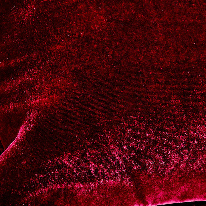 Close-up of vibrant red textured fabric with varying light reflections.