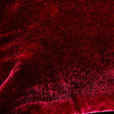 Close-up of vibrant red textured fabric with varying light reflections.
