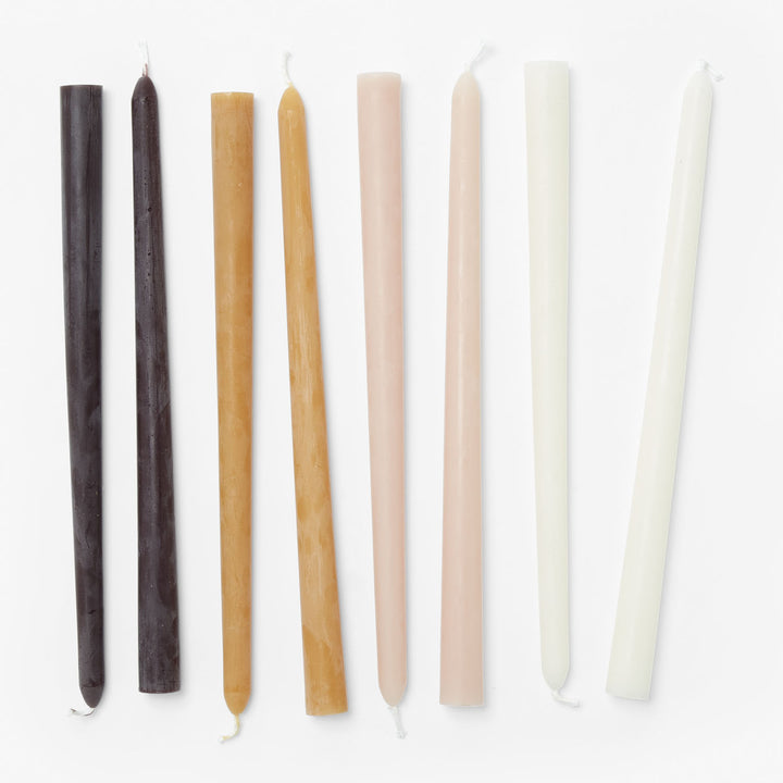Seven taper candles in gradient shades arranged neatly on white.