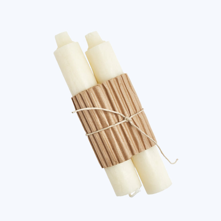 Three white candles bundled with twine on cardboard packaging.