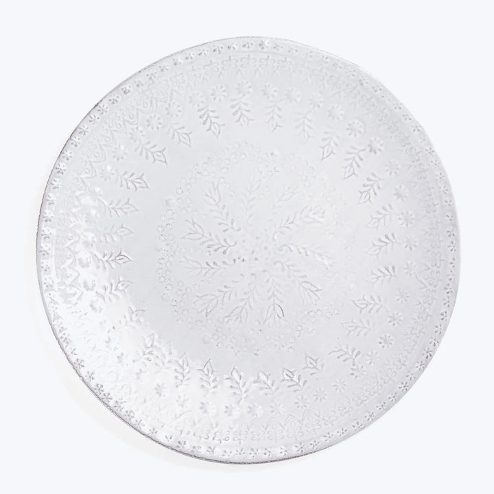 Intricately designed white plate with floral and symmetrical motifs.