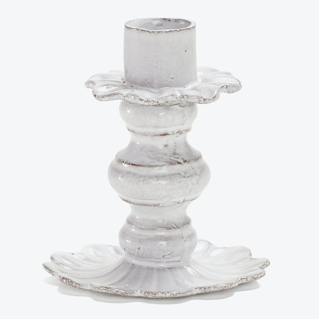 Distressed white candlestick holder with ornate flower-shaped base and bulbous stem
