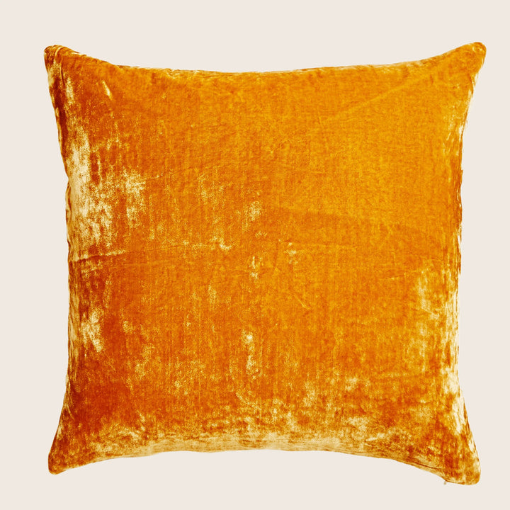 Vibrant orange velvet pillow with lush texture against white background.