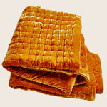Folded orange velvet quilt with quilted design for ultimate comfort.
