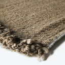 Close-up of a woolen rug with textured pattern and fringe detail.