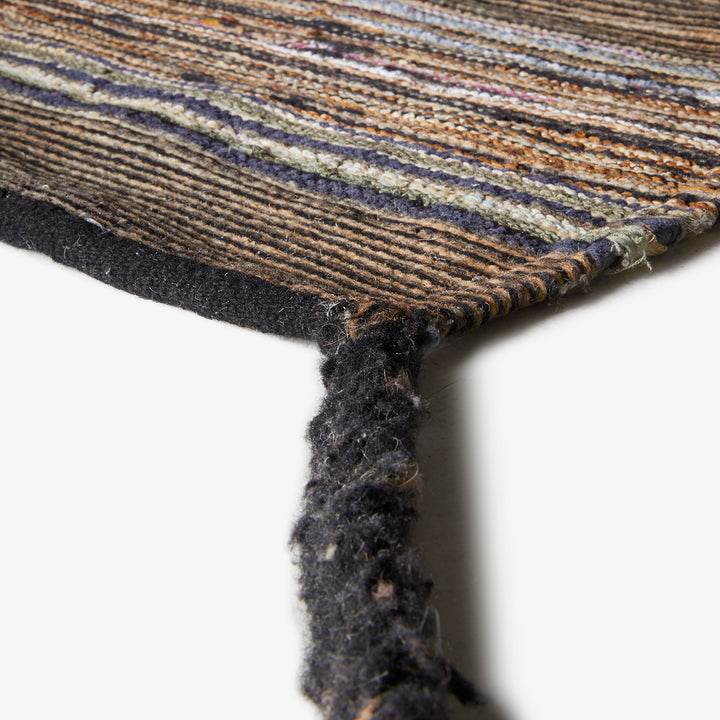 Close-up of a striped, worn rug with frayed edges.