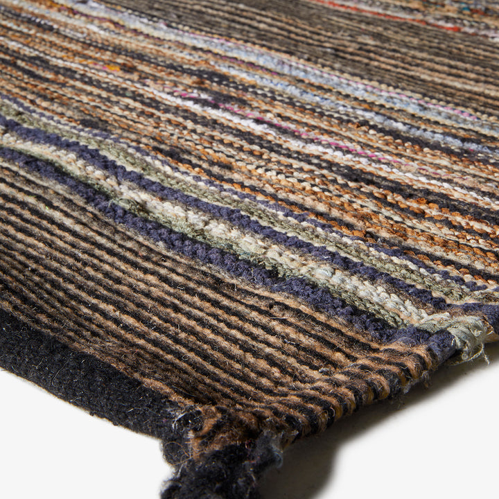 Close-up of a heavily textured, multicolored woven rug with ribbed pattern
