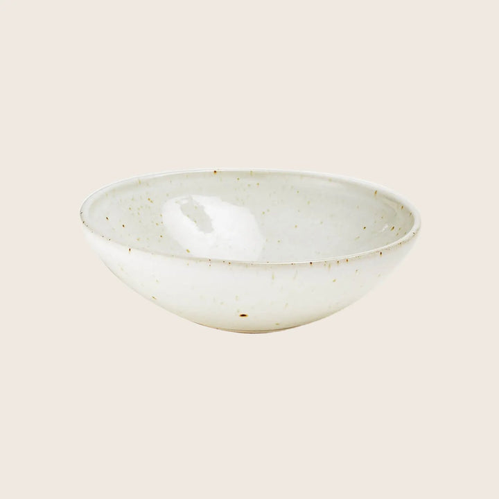 Off-white ceramic bowl with speckled pattern on white background.