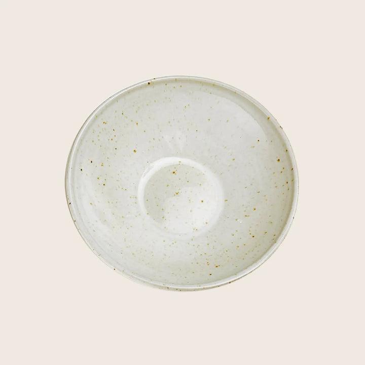 Rustic ceramic saucer with brown speckles on white background.
