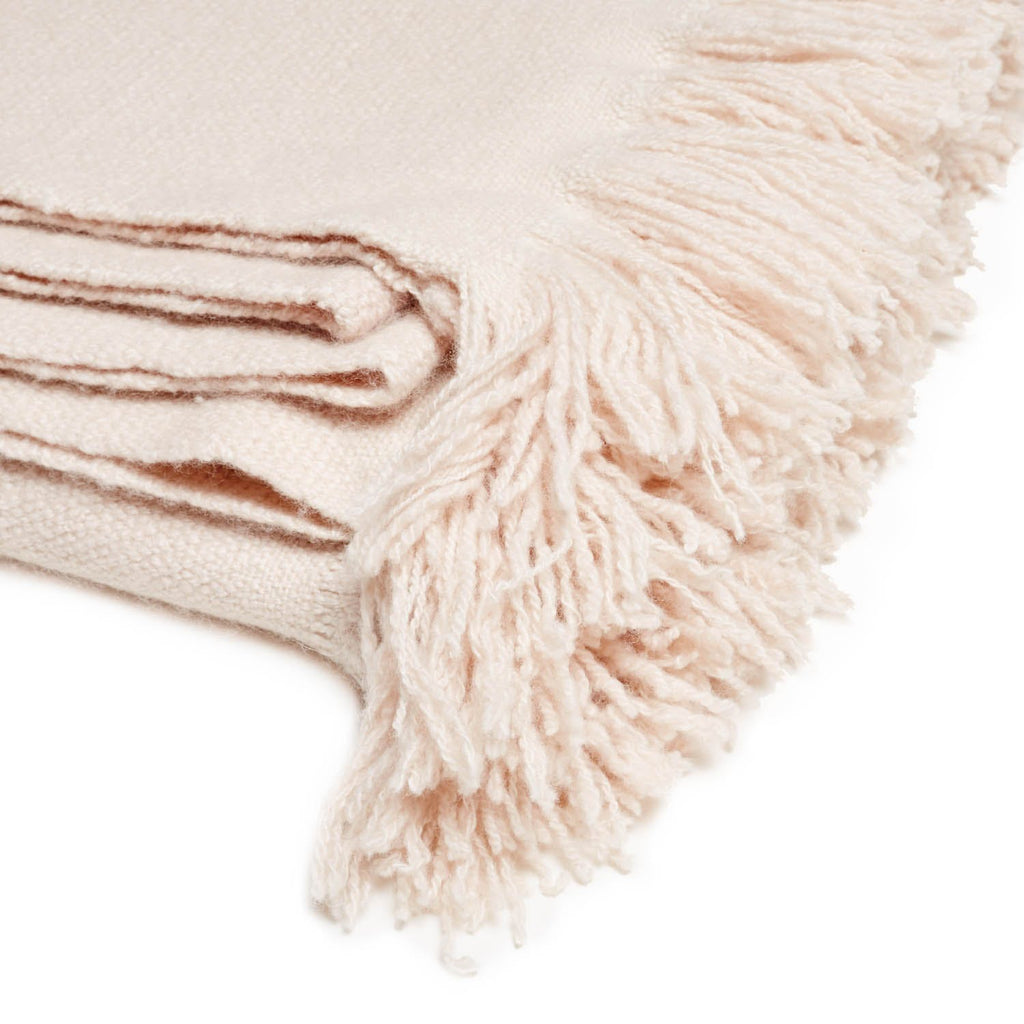 Soft and cozy cream blanket with decorative fringe detail.