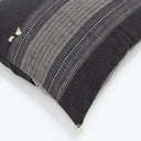 Close-up view of dark-colored cushion with geometric patterns and tassel.