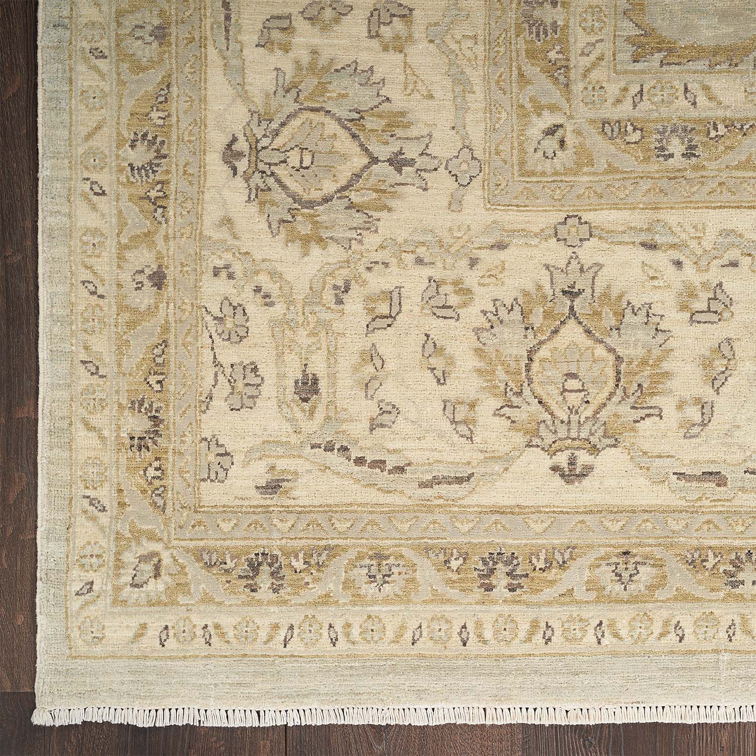 Close-up of a symmetrical, floral and geometric rug with neutral colors and fringe detail.