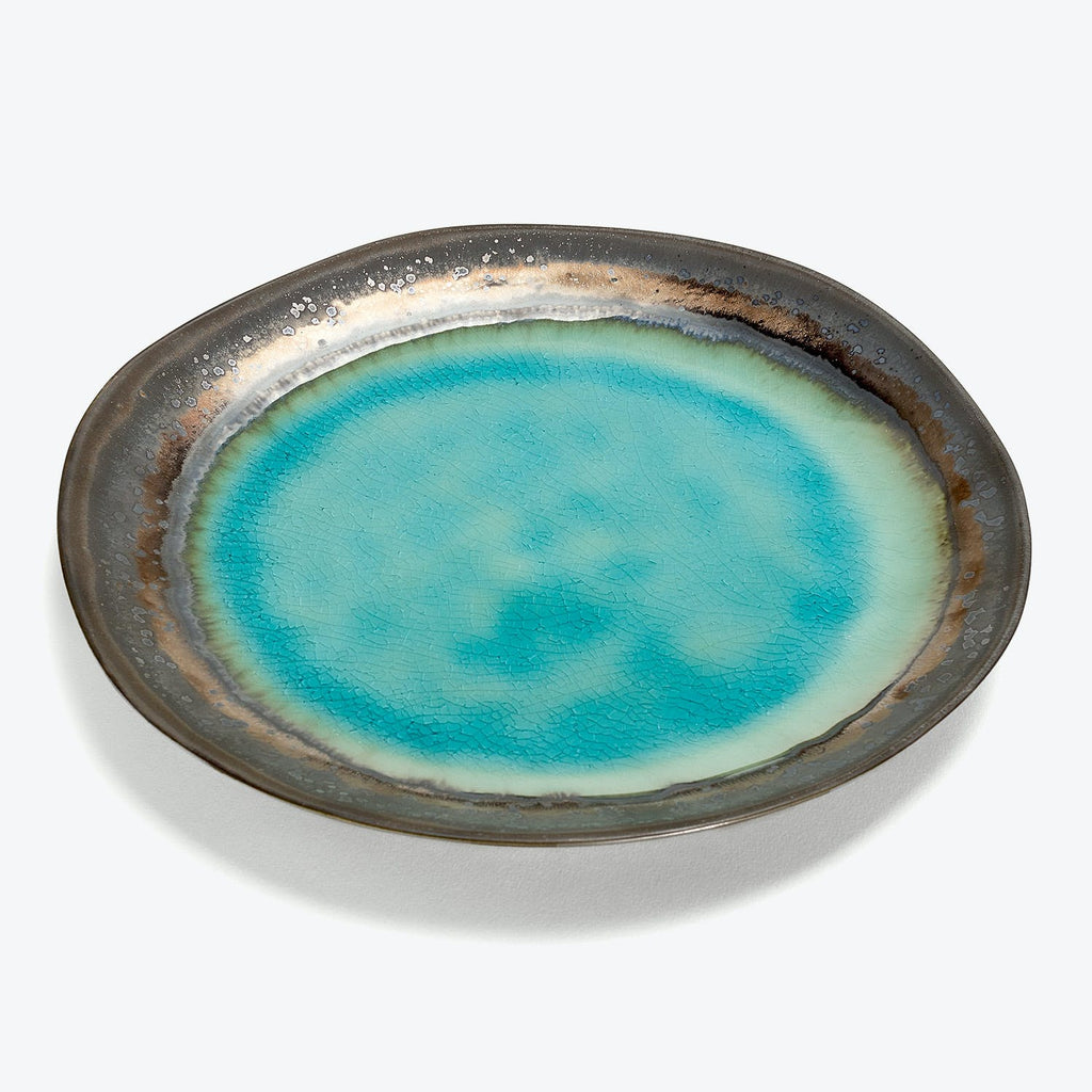 Handcrafted ceramic plate with vibrant turquoise center and crackled texture.
