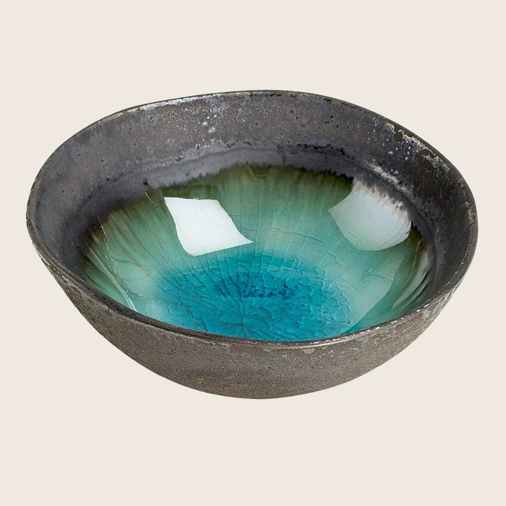 Artistic ceramic bowl with dark metallic exterior and vibrant turquoise interior