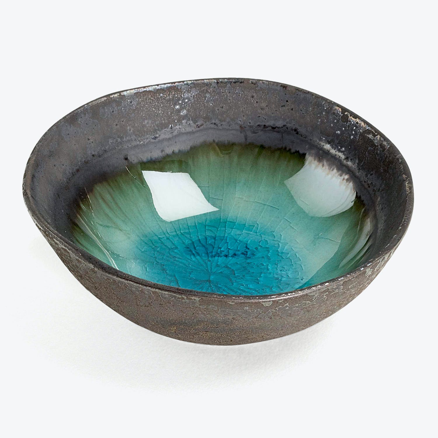 Artistic ceramic bowl with dark metallic exterior and vibrant turquoise interior