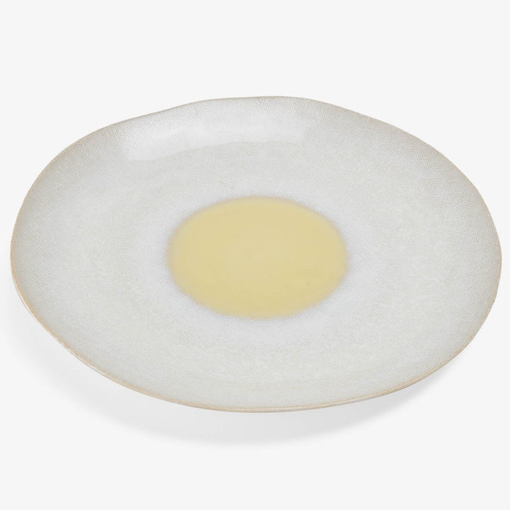 Round, off-white dish with textured surface and yellow center