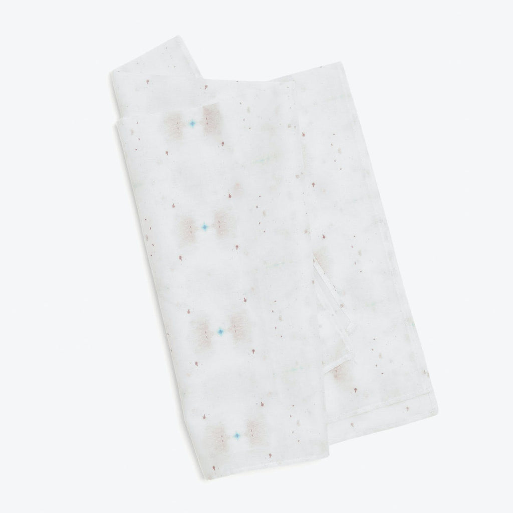 Folded paper towel with colorful spots resembling watercolor stains.