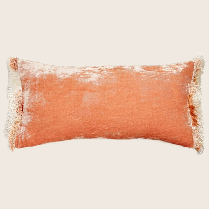 Rectangular crushed velvet throw pillow in peach with fringed edges.