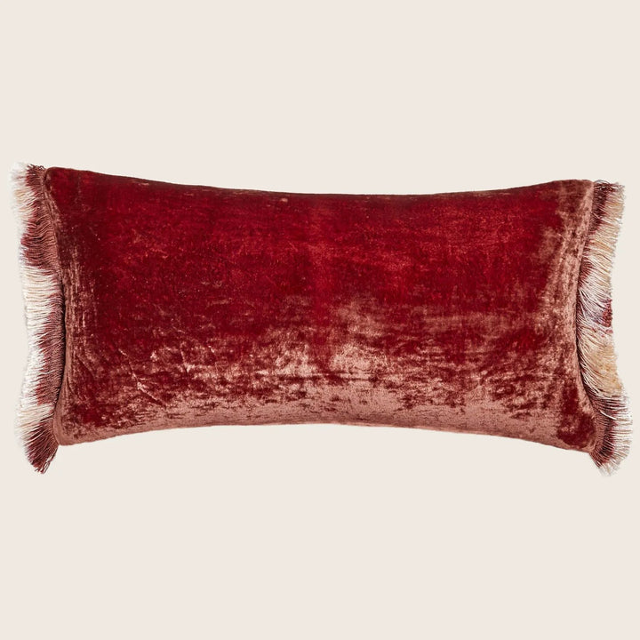 Rectangular red velvet cushion with fringe edges on white background.