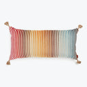 Rectangular decorative pillow with tassels in colorful gradient pattern.