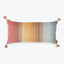Rectangular decorative pillow with tassels in colorful gradient pattern.