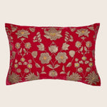 Rectangular red velvet pillow with golden embroidered floral pattern.
