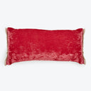 Luxurious red velvet pillow with decorative fringe borders on display.