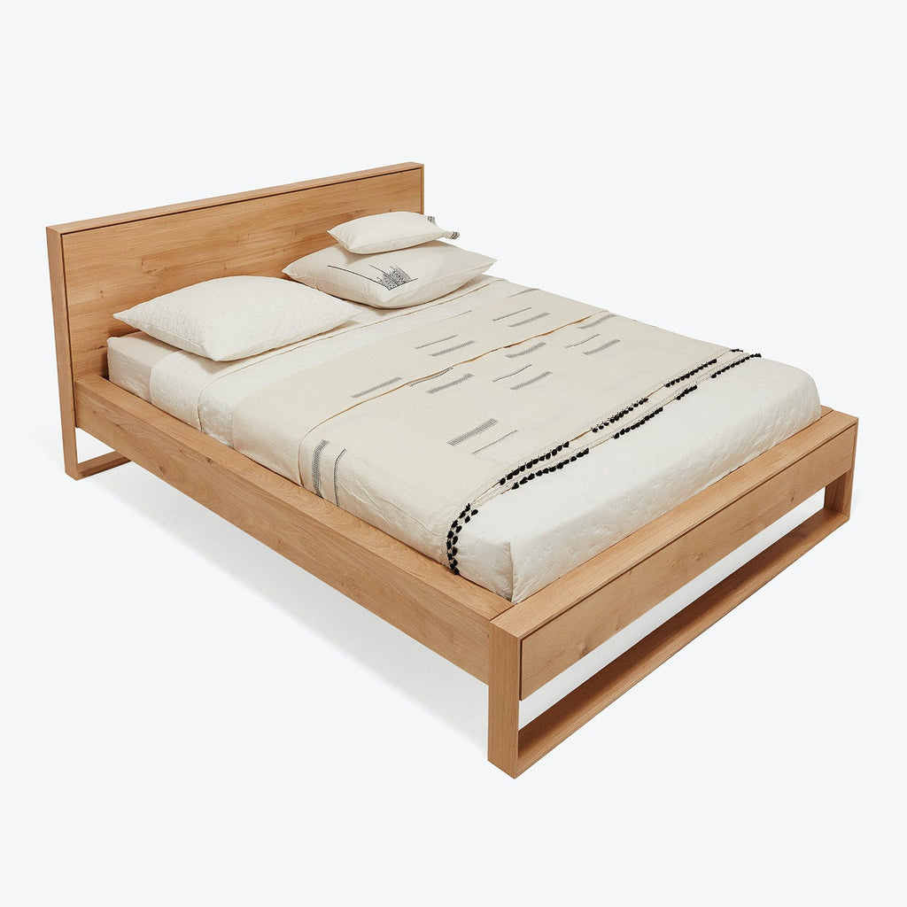 Modern wooden bed frame with neatly arranged bedding and accents.