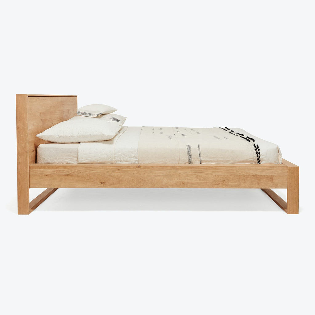 Minimalist-style single bed with light-colored wood and natural wood grain.