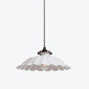 Vintage pendant light fixture with scalloped shade emits warm glow.