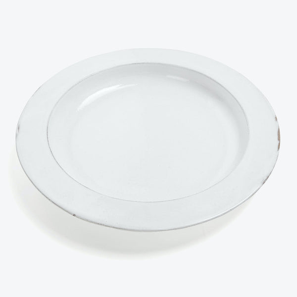 Plain white, circular plate with a chip on the edge.