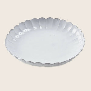 White ceramic plate with scalloped edge adds elegance to dining.
