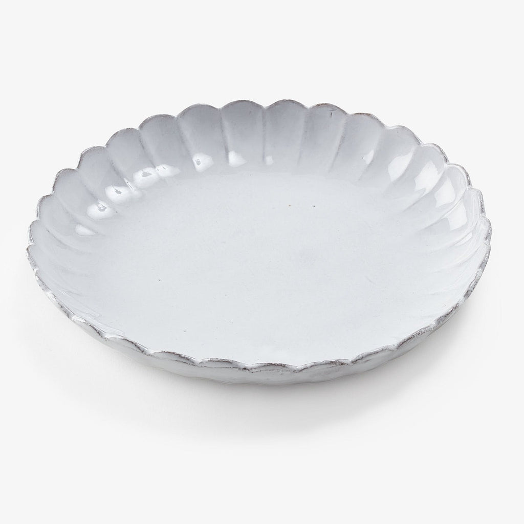 White ceramic plate with scalloped edge adds elegance to dining.