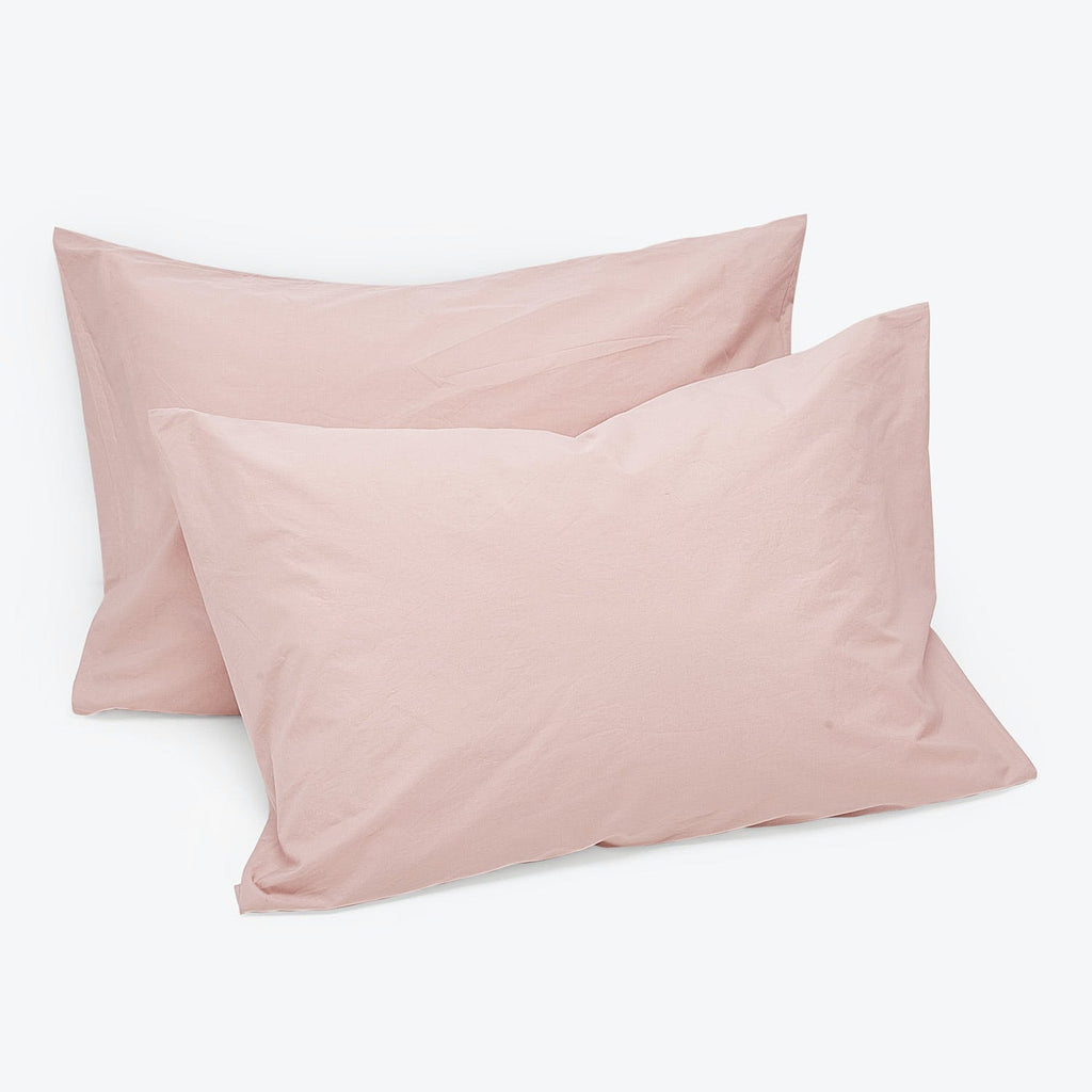 Two pale pink rectangular pillows made of smooth cotton fabric.